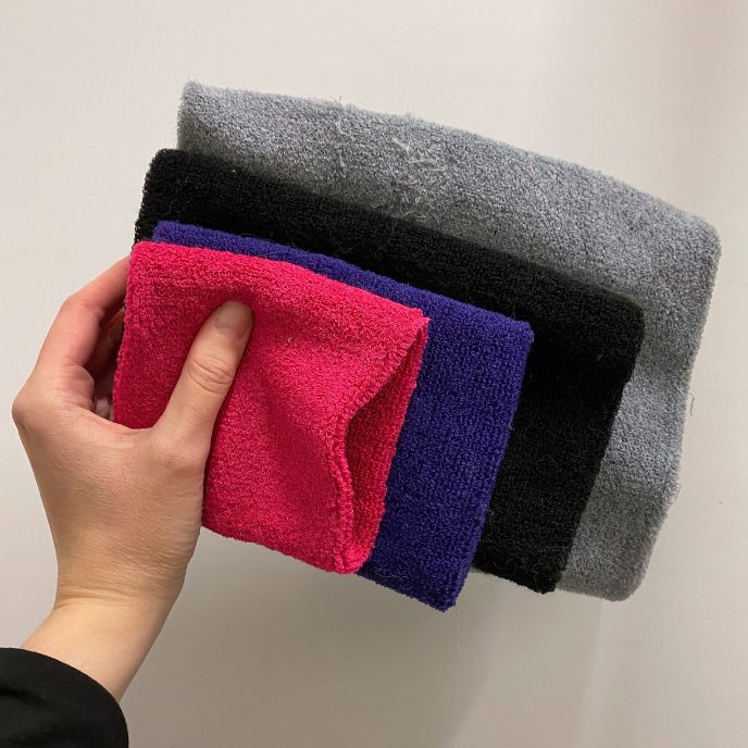 Käsi pitää neljää eri kokoista koirien korvahuppua, joka on langasta neulottu tuubi